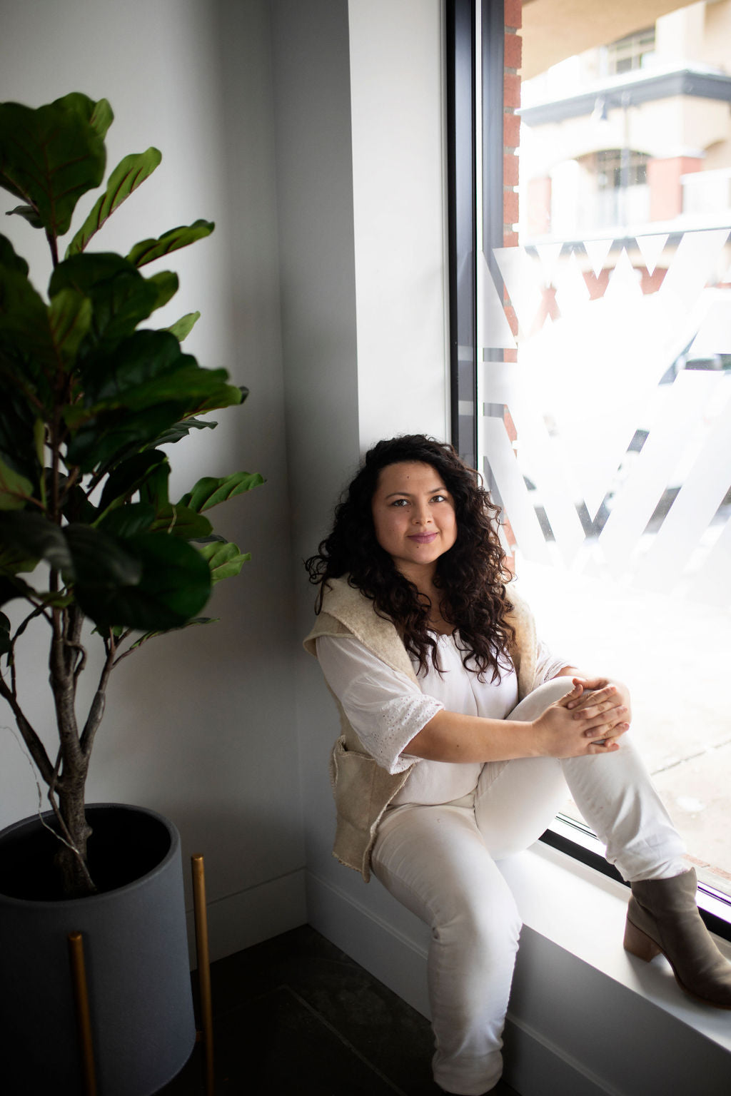 Woman sitting by a window with a plant next to her
